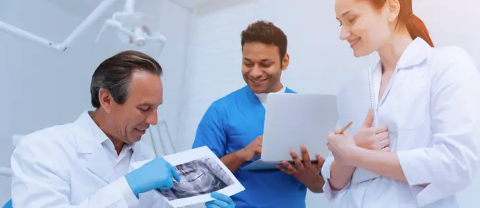 Two dentists and an assistance review an xray